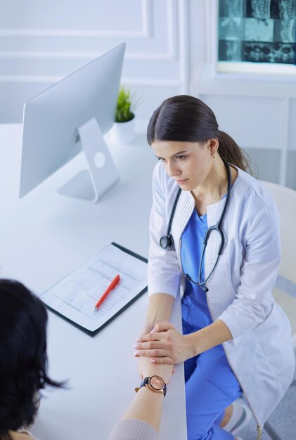 Female doctor calming down a patient at a hospital consulting room holding her hand