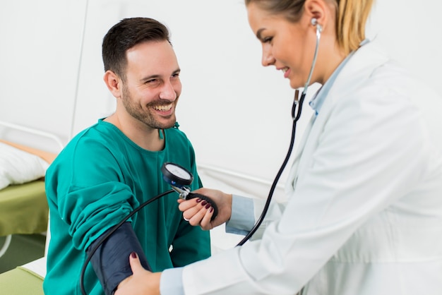 Foto medico femminile che controlla pressione sanguigna di un paziente alla clinica