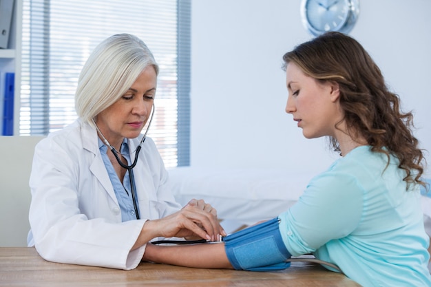 Female doctor checking blood pressure of a patient