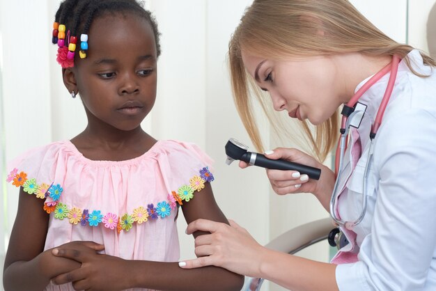 Female doctor checking skin of girl with special device.