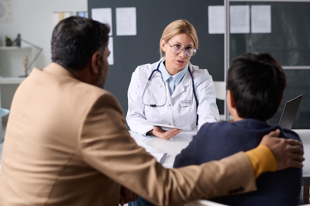 Female doctor consulting father and son