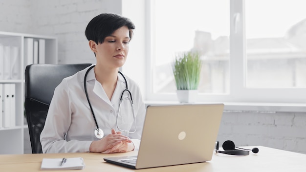 Female doctor consulting patient remote online using web camera on laptop