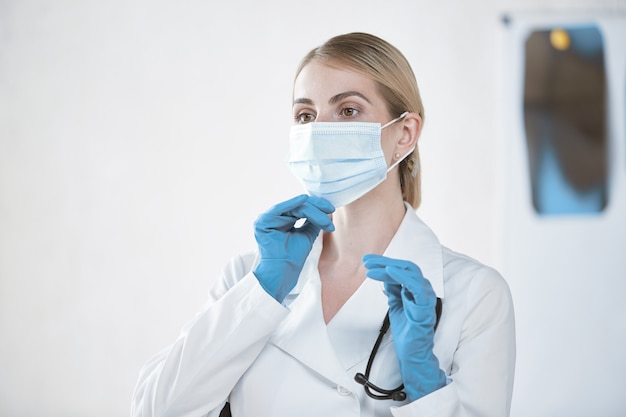 A female doctor corrects a medical mask before work