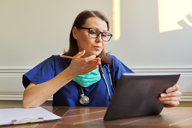 Female doctor counseling, helping patient online, medic using digital tablet for video call. Technology, medicine, healthcare, people concept