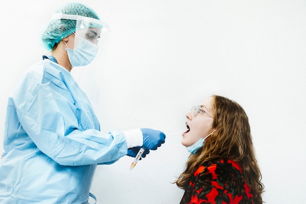 A female doctor do a covid test (PCR) to a patient by using a nasal swab to get a fluid sample.