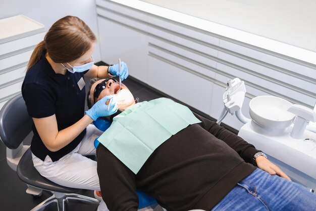 Female doctor dentist examines the teeth of a male patient