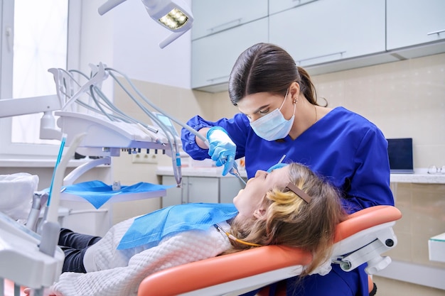 Female doctor dentist treats teeth to a child girl using anesthesia Treatment dentistry children health dental care concept