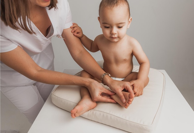 Female doctor doing foot massage to one-year-old baby. maternal care. healthy lifestyle.