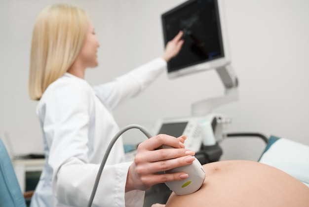 Female doctor doing ultrasound exam of pregnant woman.