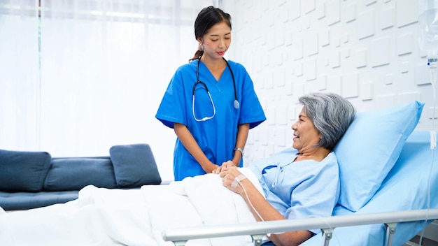 Foto una dottoressa entra nella stanza del paziente per informarsi sui sintomi di una donna anziana che stava ricevendo soluzione salina in un letto nella stanza del paziente