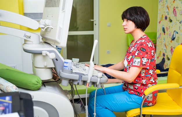 Female doctor examining boy with ultrasonic equipment at hospital.