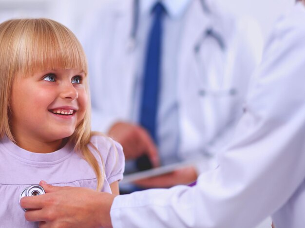 Female doctor examining child with stethoscope at surgery