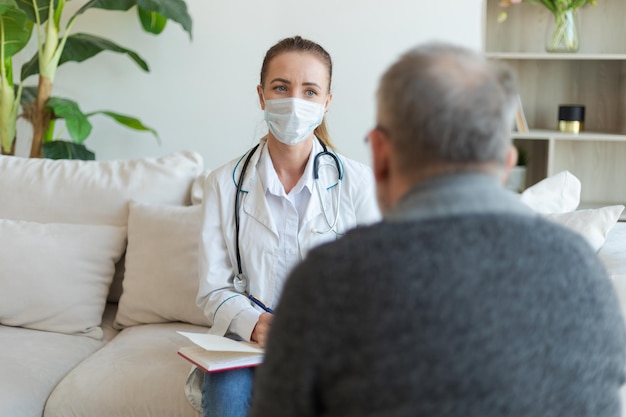 Female doctor examining older senior man in doctor office or at home old man patient and doctor have