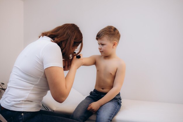 Photo female doctor examining skin of little boy with dermatoscope