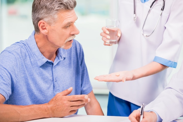 Female doctor giving a pill to mature patient.