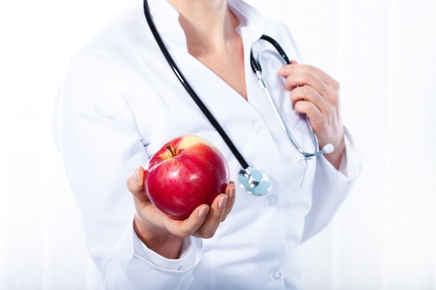 Female doctor giving a red apple