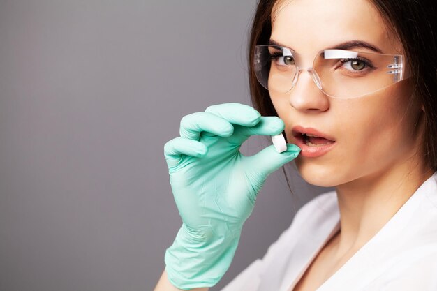 Female doctor in gloves holds a pill for treatment.