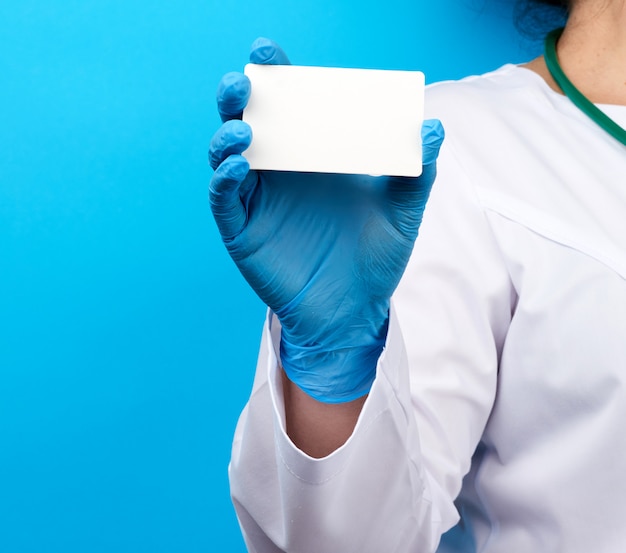 Female doctor hand in blue medical latex gloves holds an empty paper business card