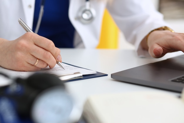 Female doctor hand hold silver pen filling patient