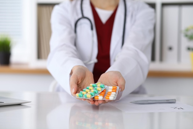 Female doctor hand holding pack of different tablet blisters at workplace closeup. Panacea, life save service, prescribe medicament concept