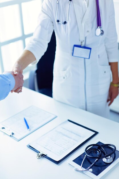 Female doctor handshaking a patient's hand and smiling