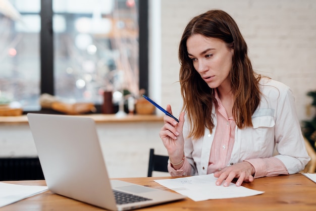 female doctor has an online appointment sitting at her desk in front of her laptop.