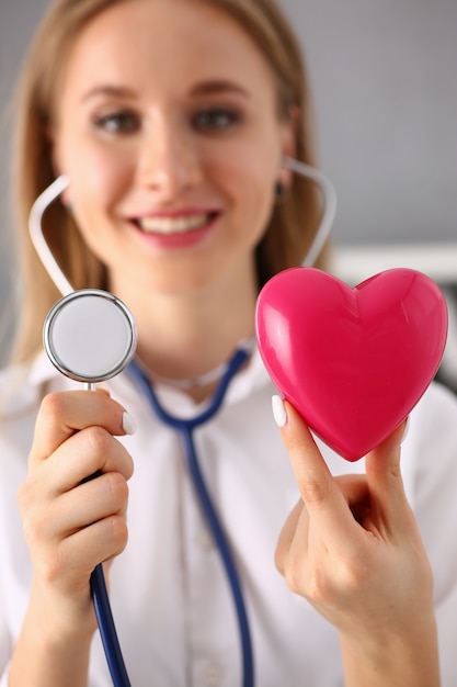 Female doctor hold in arms red heart and phonendoscope