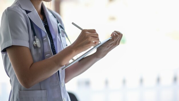 Female doctor hold digital tablet and writing in touch screen in office