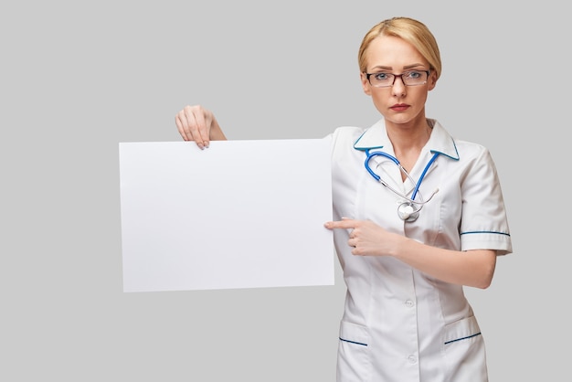 Female doctor holding a blank paper sheet or poster