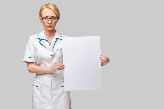 白紙のシートまたはポスターを保持している女性医師