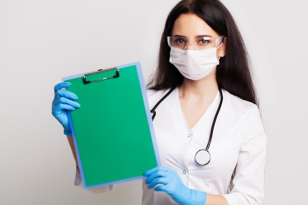 Female doctor holding a blank sheet of paper with space for text