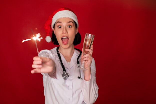 female doctor holding glass of champagne and burning sparklers in her hands