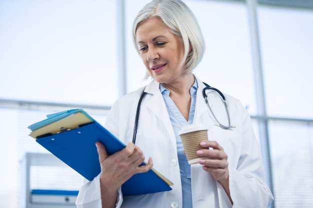 의료 파일 및 커피 컵을 들고 여성 의사