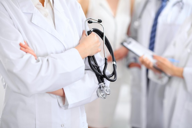 Female doctor holding a stethoscope in his hand two doctors and patient are on the background