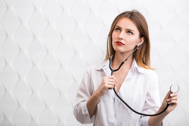 Female doctor holding stethoscope wearing doctors smock cheerful caucasian woman isolated before white background