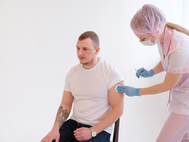 FEMale doctor holding syringe making covid 19 vaccination injection dose in shoulder of male patient