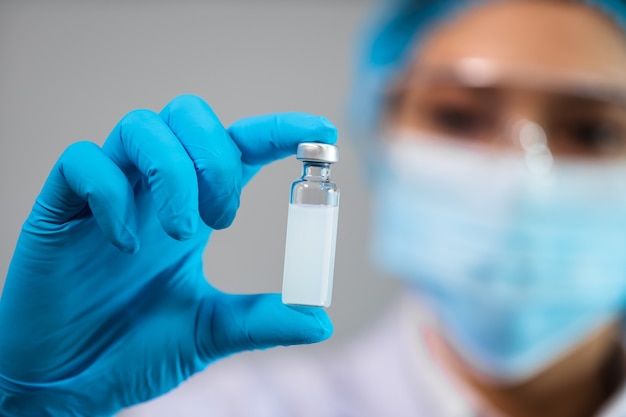 Female doctor holding vaccine bottle for injection medicine