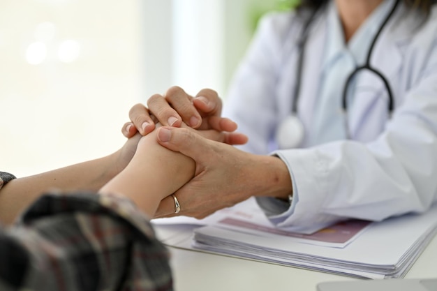 女医は若い患者の手を握り、健康診断中にサポートを提供し、彼女を安心させます