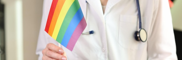 Photo female doctor holds rainbow lgbt flag in her hand concept of medical help after reassignment