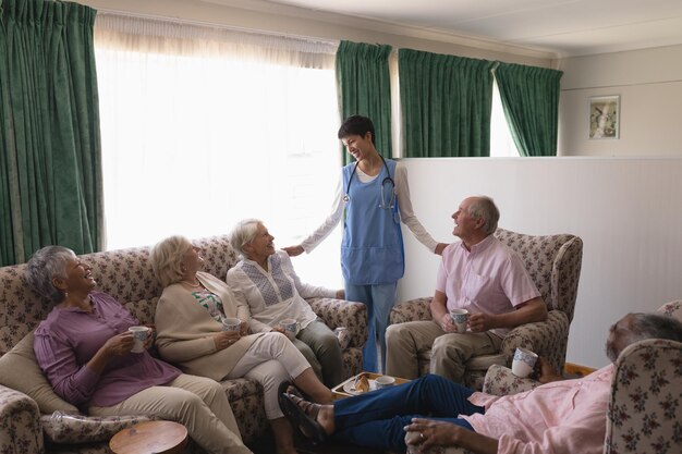 Foto dottoressa che interagisce con persone anziane nel soggiorno