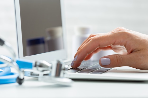 Female doctor is typing in laptop computer