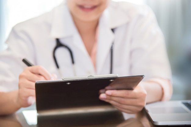 female doctor is writing something on clipboard.