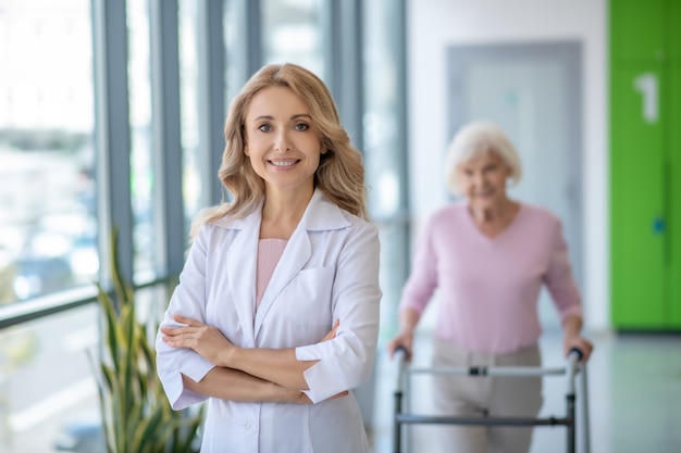 Female doctor in a lab coat standing with arms crossed and smiling