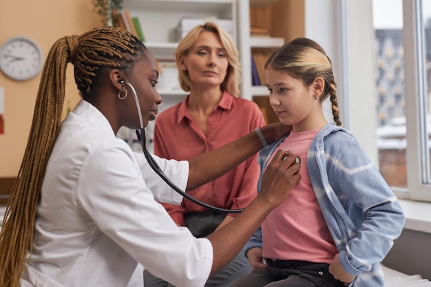 Female doctor listening to childs breathing with stethoscope