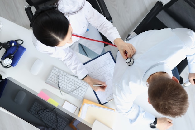 Female doctor listens to lungs of male patient at reception top view lung disease diagnosis