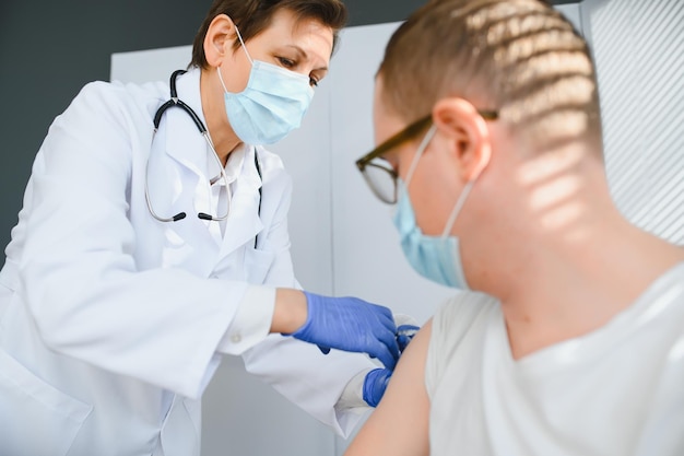 Female doctor making injecting using syringe to male patient in hospital Senior man taking injection for flu in clinic Female doctor vaccinating a man