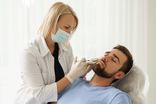 Photo female doctor and male client during filler injections in aesthetic medical clinic