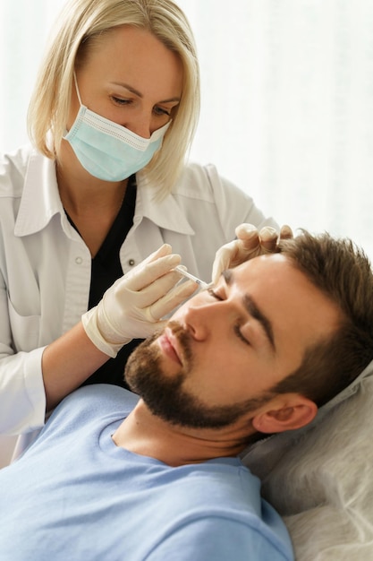 Female doctor and male client during filler injections in aesthetic medical clinic