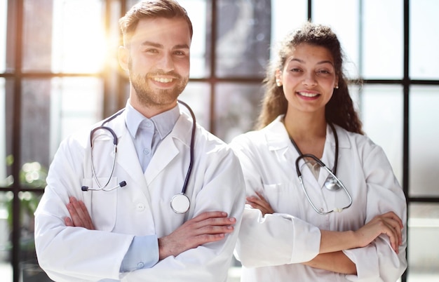 A female doctor and a male doctor are standing in the office with their arms crossed