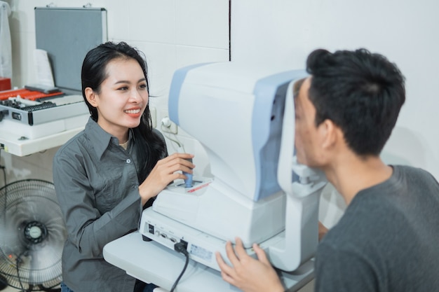 A female doctor and a male patient doing an eye check using a device at an eye clinic